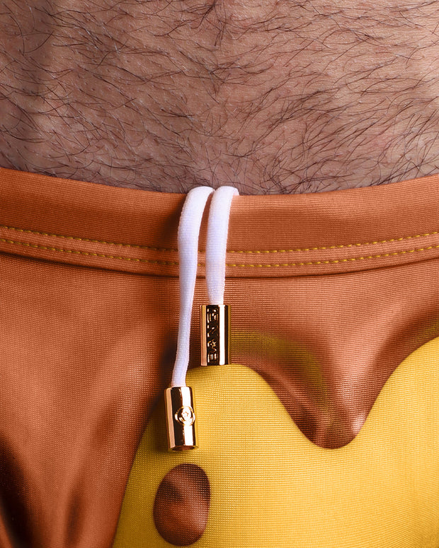 Close-up view of the CHOCO BANG men’s drawstring briefs showing white cord with custom branded golden cord ends, and matching custom eyelet trims in gold.