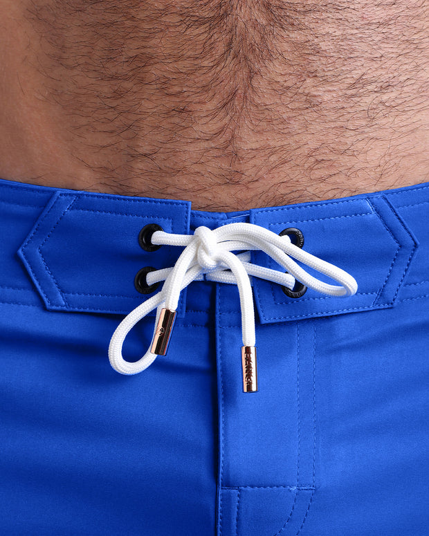 Close-up view of inseam and details of these shorts for men, with white cord and custom branded golden cord-ends, and matching custom eyelet trims in gold.
