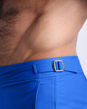 Close-up view of the CLUB BLUE men’s swimwear, showing custom branded golden adjustable side buckles.