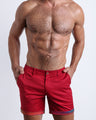 Front view of a male model wearing CONFESSIONS ON A RED FLOOR men's chino shorts in bright red color with reversible cuffs exposing a fun print by BANG! Miami Clothes brand. 