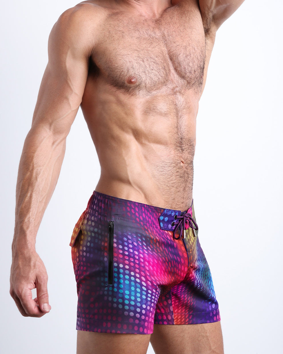 Side view of a man wearing the CONFESSIONS ON A SAND FLOOR shorter leg length swimming shorts with side zipper pocket in a disco ball print by BANG! Clothes.