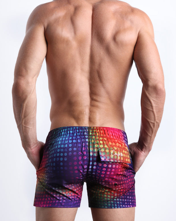 Back view of a man wearing the CONFESSIONS ON A SAND FLOOR shorter leg length swimming shorts with side zipper pocket in a disco ball print by BANG! Clothes.