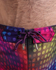 Close-up view of men’s summer beach shorts by BANG! clothing brand, showing purple cord with custom branded golden cord ends, and matching custom eyelet trims in gold.