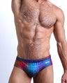 Front view of model wearing the CONFESSIONS ON A SAND FLOOR men’s bikini-style bottoms in a pop color disco ball print in purple, blue, red and yellow by the Bang! Clothes brand of men's beachwear from Miami.
