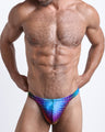 Frontal view of a sexy male model wearing men’s bikini-style thong featuring CONFESSIONS ON A SAND FLOOR in a multi color disco ball inspired by Madonna, Abba, and Studio 54 by the Bang! Menswear brand from Miami.