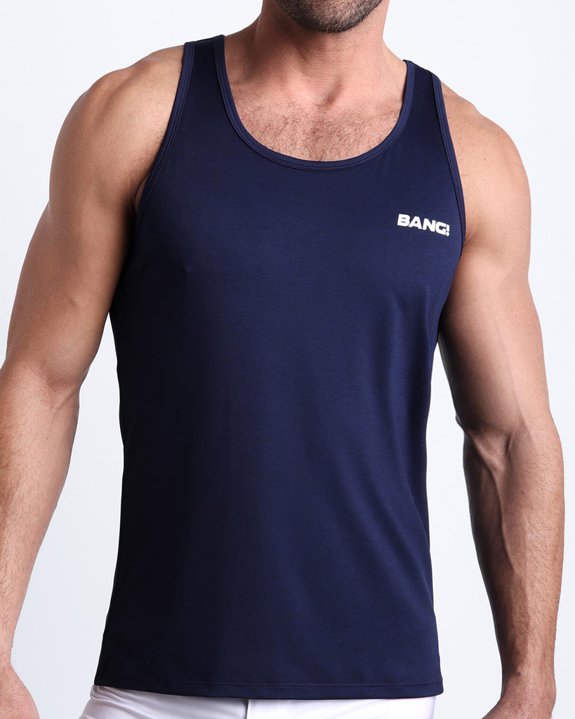 Frontal view of male model wearing the CORE BLUE in a solid dark navy color gym tank top for men by the Bang! brand of men's beachwear from Miami.