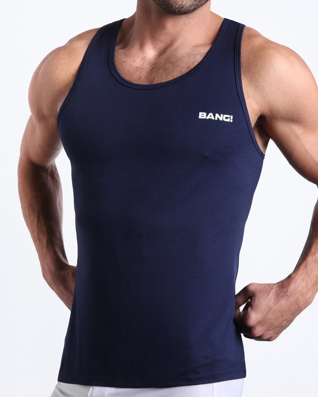 Side view of men’s workout tank top in CORE BLUE a dark blue color with white logo made by BANG! Clothing the official brand of mens beachwear. 