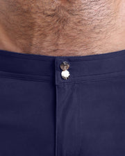 Close-up view of men’s summer beach shorts by BANG! clothing brand, showing custom branded golden buttons.