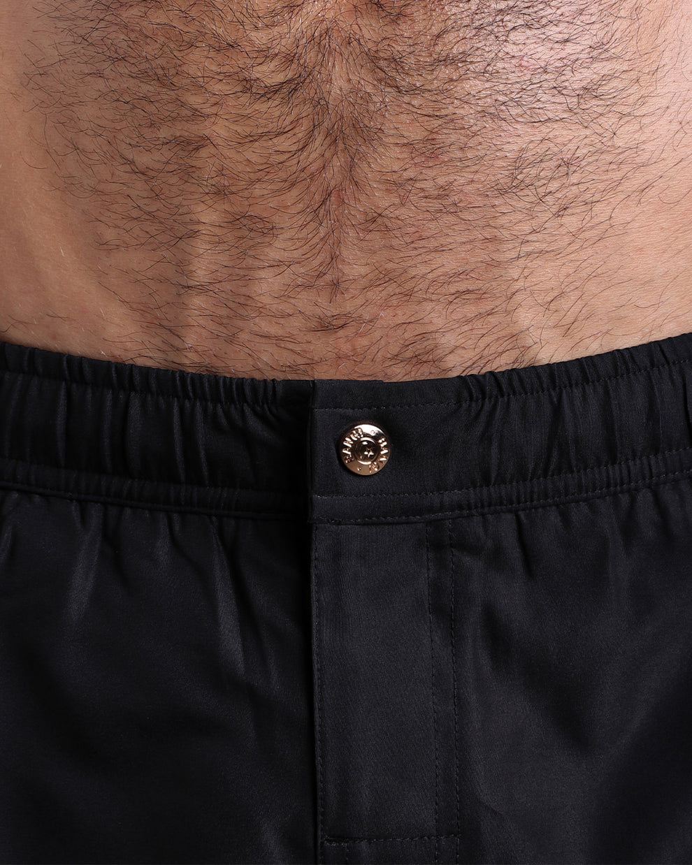 Close-up view of the men’s summer mini shorts, showing custom branded metal button in gold.