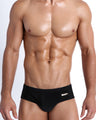 Frontal view of a sexy male model wearing men’s Dark Knight swimsuit in black by the Bang! Menswear brand from Miami.