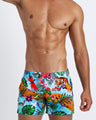 Front view of a male model wearing Disco Jungle tropical print flex shorts by Bang! brand of men's beachwear from Miami.