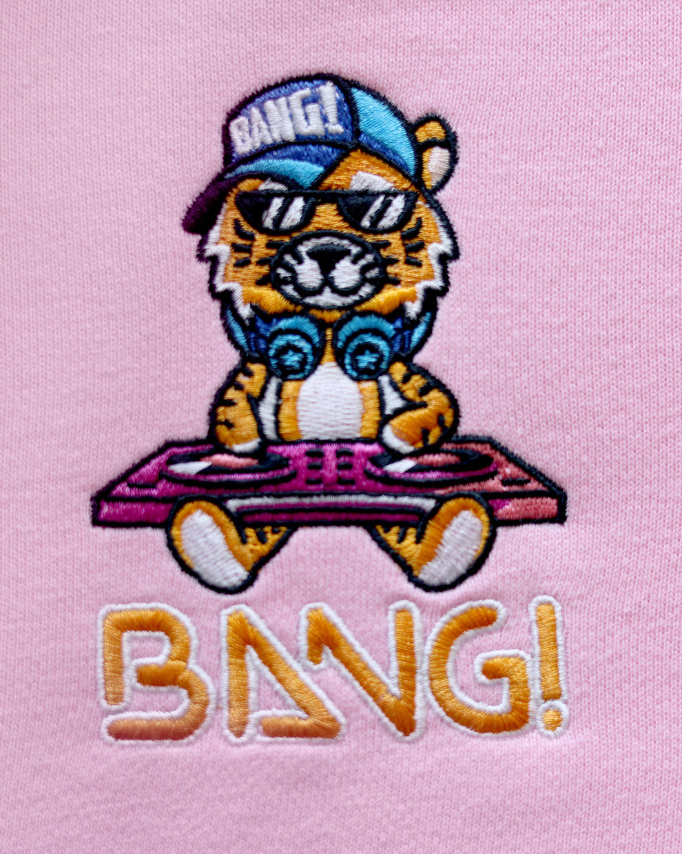 Close-up image of the embroidered BANG! Logo featuring the brands signature MISTER TJ character with clubbing and disc-jockey details in bright colors.