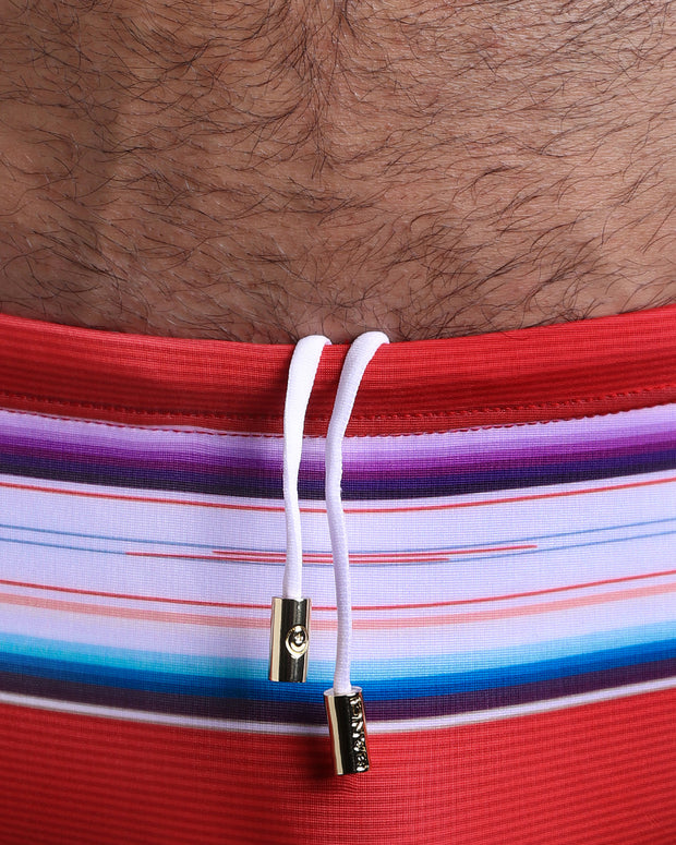 Close-up view of the FAWCETT SARAPE Swim Sunga mens swimsuit with red and white stripes inspired by a Mexican blanket with an internal drawstring cord in white showing custom branded golden buttons by BANG! clothing brand.