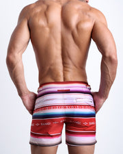 Back view of male model wearing the FAWCERR SARAPE beach trunks for men by BANG! Miami inspired by the mexican blanket in Farrah Fawcett 1976 famous swimsuit poster by Bruce McBroom.