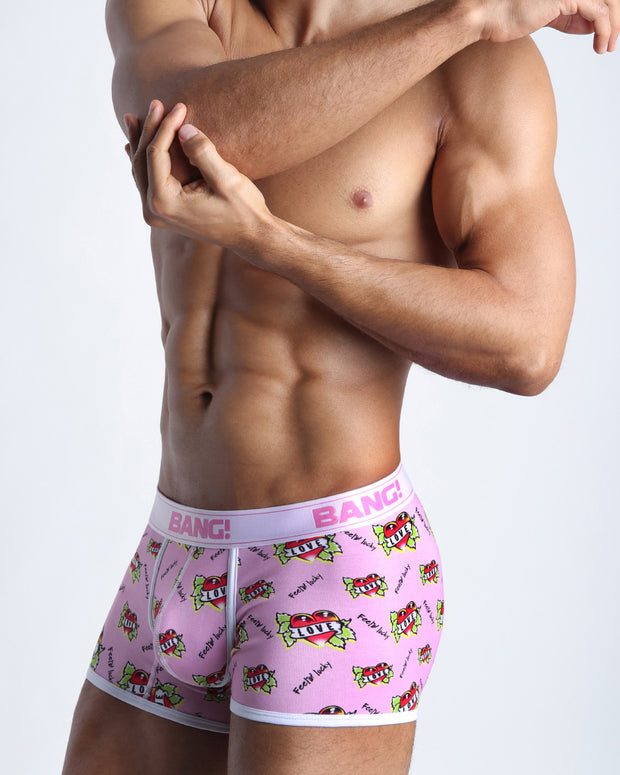 Side view of a sexy male model wearing a BANG! Cotton Boxer Briefs for men in in pink with heart and arrows pop art. Offers stay-put leg design that prevents chafing and riding up the leg. 