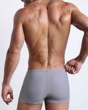 Back view of a male model wearing the GREY ANATOMY men’s swim trunks in a solid grey color by the Bang! Clothes brand of men's beachwear from Miami.