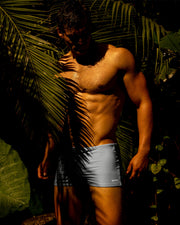Sexy male model in a jungle wearing his GREY ANATOMY Swim Trunks a solid gray color perfect for in or out of the beach or pool by BANG! Clothes a mens' beachwear brand.