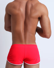 Back view of a male model wearing men’s swim brief in red by the Bang! Clothes brand of men's beachwear from Miami.