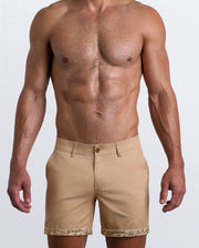 Front view of a male model wearing LET'S HAVE A KHAKI men's chino shorts in a solid light tan color with reversible cuffs exposing a fun Toile De Jouy print by BANG! Miami Clothes brand.
