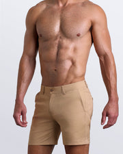 Side view of stretchy men's shorts in LET'S HAVE A KHAKI a beige color with with two front pockets and custom engraved button front closure with zip fly from BANG! Clothing. 