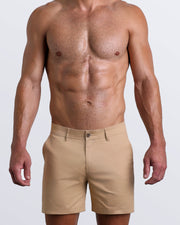 Front view of a male model wearing LET'S HAVE A KHAKI men's chino shorts in a solid light tan color with reversible cuffs exposing a fun Toile De Jouy print by BANG! Miami Clothes brand.