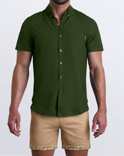 Model wearing LET'S HAVE A KHAKI men's chino shorts in a solid light tan color with reversible cuffs exposing a fun Toile De Jouy print and the ALPHA GREEN mens short-sleeve stretch shirt in a military green color by BANG! men's clothing brand.