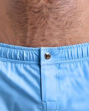 Close-up view of the men’s summer mini shorts, showing custom branded metal button in gold.