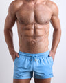 Male model wearing the MAGNET BLUE men’s swim shorts in sky blue color by the Bang! brand of men's beachwear from Miami.