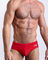 Frontal view of a sexy male model wearing men’s swimsuit in red by the Bang! Menswear brand from Miami.