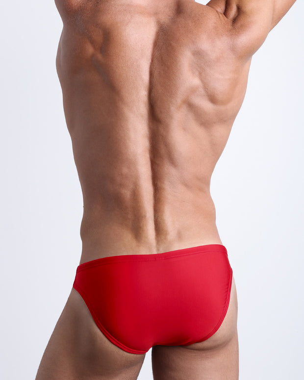Back view of male model wearing the MAJESTIC RED beach mini-briefs for men by BANG! Miami in red color.