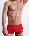 Frontal view of a sexy male model wearing men’s swimsuit in bright red color by the Bang! Menswear brand from Miami.