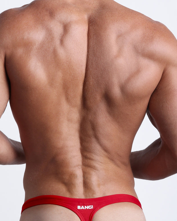 Back view of a male model wearing men’s MAJESTIC RED swim thongs in true red color by the Bang! Clothes brand of men&