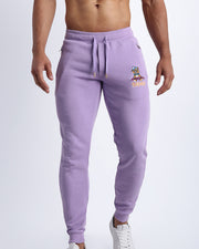 Frontal view of male model wearing the BANG! Clothes METRO PURPLE Tracksuit Pants with frontal drawstring closure. This athletic jogger has an embroidered Bang! Logo with the signature Mister TJ tiger. 