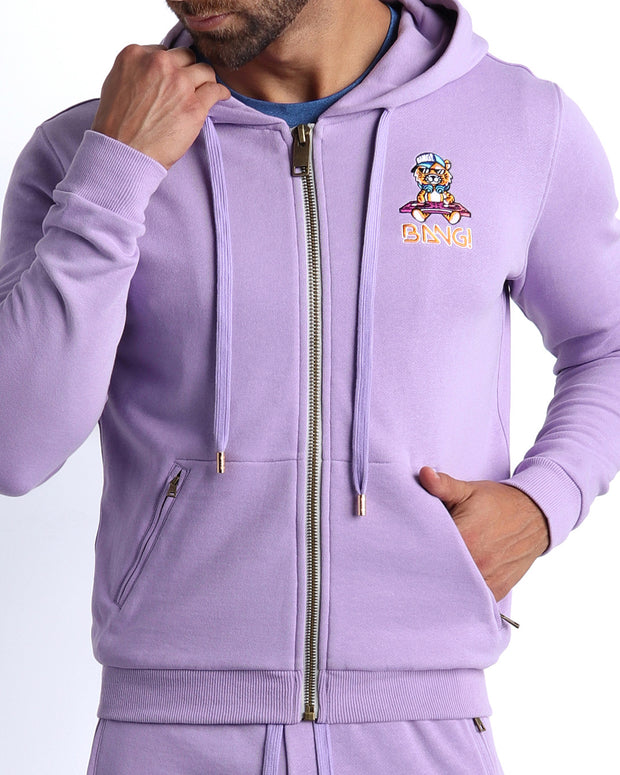 Frontal view of male model wearing the BANG! Clothes METRO PURPLE Tracksuit Hoodie Jacket with frontal zipper closure. This long-sleeve jacket has an embroidered Bang! Logo with the signature Mister TJ tiger. 