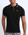Front view of a sexy male model wearing a premium 100% Cotton Pique Polo Shirt for men from BANG! Brand in a black color.