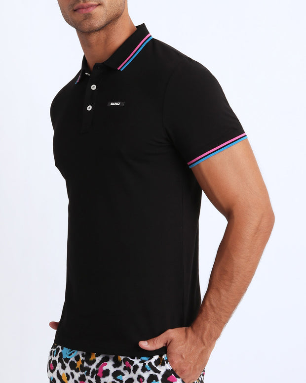 Back view of a sexy model wearing a short-sleeve classic polo shirt for men in a black color from BANG! Clothing the official brand for menswear.