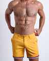 Front view of a male model wearing MUSTARD ON 45 men's chino shorts in a solid sunny yellow color with reversible cuffs exposing a fun print by BANG! Miami Clothes brand. 