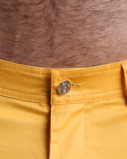 Close up view of cotton fabric chino street shorts with custom engraved front tack button in golden finish by BANG! men's clothing brand.