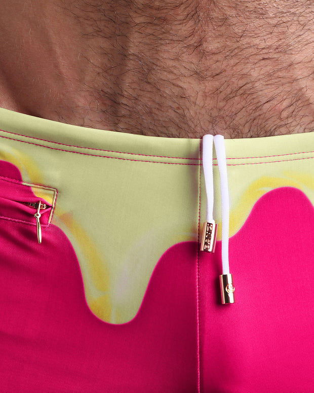 Close-up view of the MY MILKSHAKE Swim Trunks mens swimsuit featuring hot bright pink and a light yellow melting ice cream theme with an internal drawstring cord in white showing custom branded golden buttons by BANG! clothing brand.