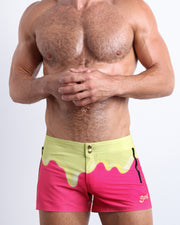 Front view of model wearing the MY MILKSHAKE men’swim bottoms in a bright pink color featuring yellow melting ice cream print by the Bang! Clothes brand of men's beachwear from Miami.