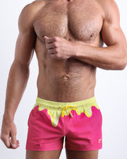 Front view of model wearing the MY MILKSHAKE men’s beach shorts in pink & yellow melting ice cream print around the waist by the Bang! Clothes brand of men's beachwear from Miami.