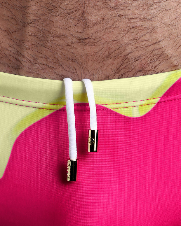Close-up view of the MY MILKSHAKE Swim Sunga mens swimsuit featuring hot bright pink and a light yellow melting ice cream theme with an internal drawstring cord in white showing custom branded golden buttons by BANG! clothing brand.