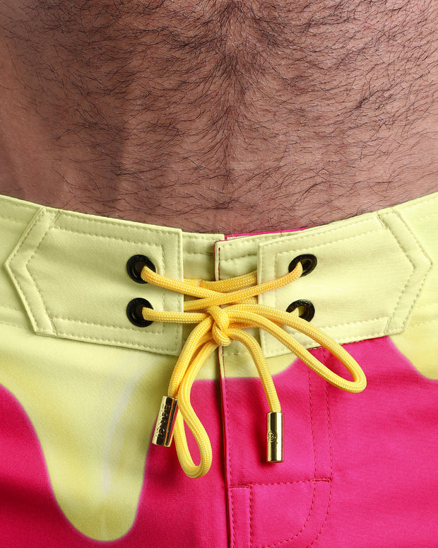 Close-up view of men’s summer beach shorts by BANG! clothing brand, showing yellow cord with custom branded golden cord ends, and matching custom eyelet trims in gold.