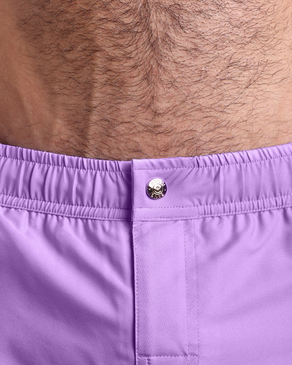 Close-up view of the men’s summer mini shorts, showing custom branded metal button in gold.