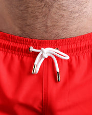 Close-up view of the PRIME RED men’s summer shorts, showing white cord with custom branded golden cord ends, and matching custom eyelet trims in gold.