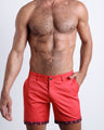 Front view of a male model wearing SHOWTIME RED men's chino shorts in bright red color with reversible cuffs exposing a fun print by BANG! Miami Clothes brand.