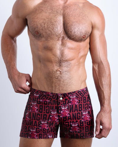 Front view of model wearing the STARSTRUCK men’swim bottoms in a red berry color with black BANG! Typography print and tiger pop art by the Bang! Clothes brand of men's beachwear from Miami.