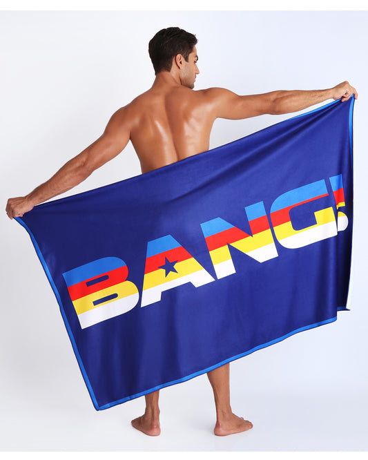 Frontal view of sexy male model showing the STRIPE'A'POSE unisex lightweight towel in blue color with color stripes in white, yellow, bold red, and blue by Bang! Clothing from Miami.