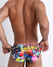 Back view of male model wearing a swim brief in vibrant fun pop-culture theme made by the Bang! Brand of men's beachwear. 