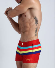 Left side view of men’s red beach trunks with color stripes, made by the Miami-based Bang! brand of men's beachwear.